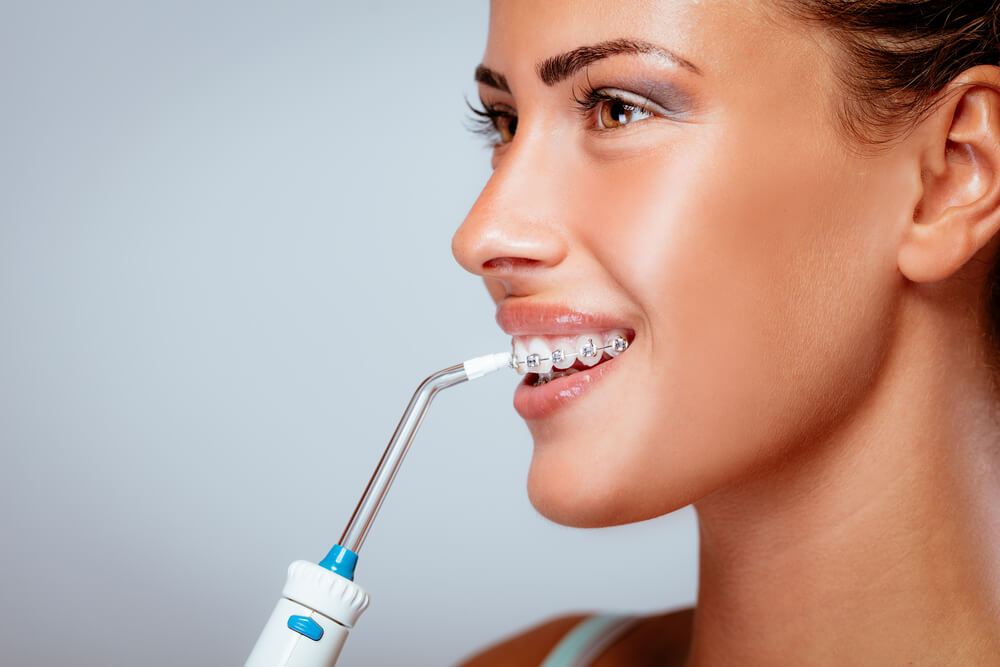 mujer con irrigador dental