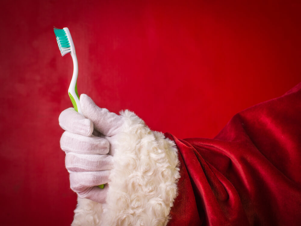 Papa Noel sujetando cepillo de dientes